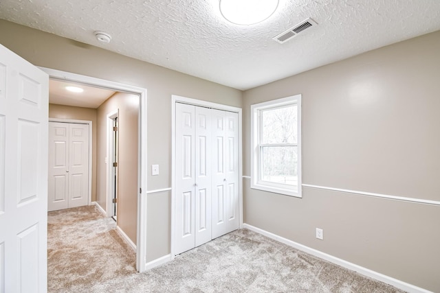 unfurnished bedroom with light carpet and a textured ceiling