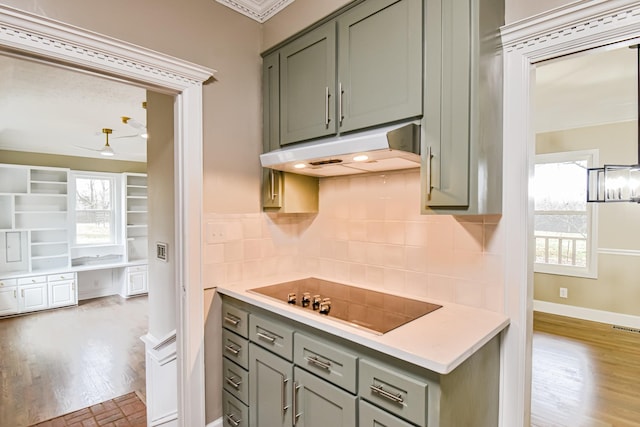 kitchen featuring black electric stovetop, a healthy amount of sunlight, backsplash, and light hardwood / wood-style flooring