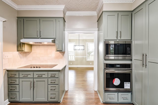 kitchen featuring an inviting chandelier, tasteful backsplash, a textured ceiling, appliances with stainless steel finishes, and ornamental molding