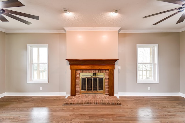 unfurnished living room with plenty of natural light, wood-type flooring, a textured ceiling, and a brick fireplace