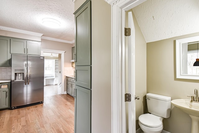 bathroom with backsplash, crown molding, toilet, a textured ceiling, and wood-type flooring