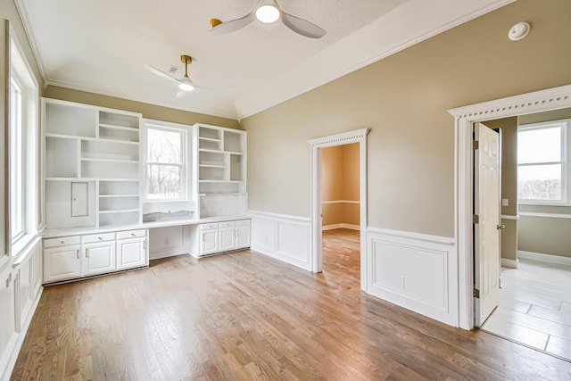 unfurnished office featuring built in desk, crown molding, and a wealth of natural light