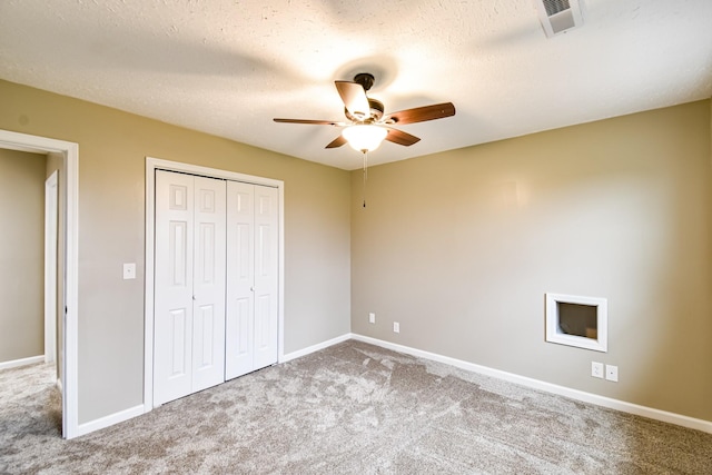 unfurnished bedroom with carpet flooring, ceiling fan, a textured ceiling, and a closet