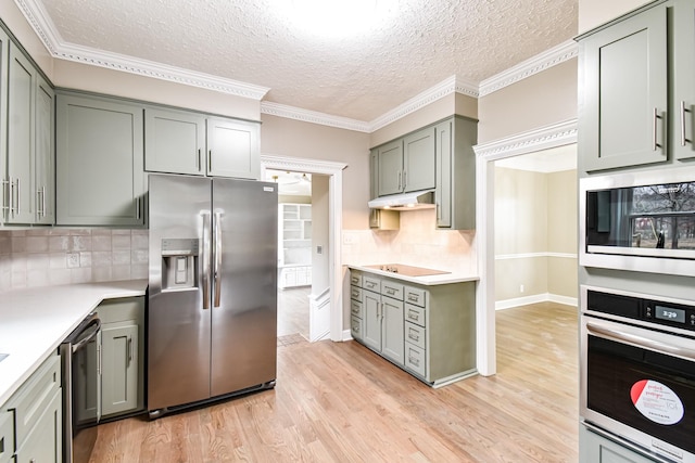 kitchen featuring a textured ceiling, stainless steel appliances, light hardwood / wood-style flooring, and tasteful backsplash