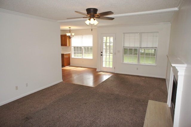 unfurnished living room with carpet, a textured ceiling, ceiling fan with notable chandelier, and crown molding