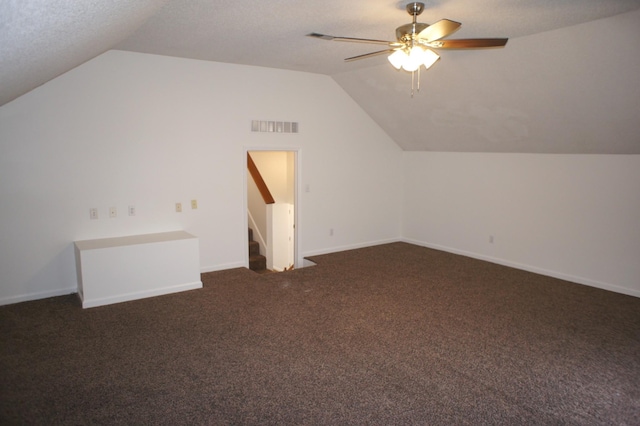 additional living space with dark colored carpet, a textured ceiling, vaulted ceiling, and ceiling fan