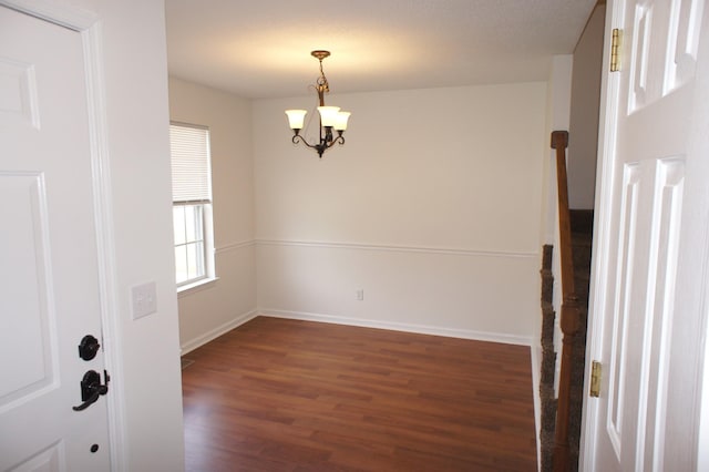 empty room with dark hardwood / wood-style flooring and a chandelier