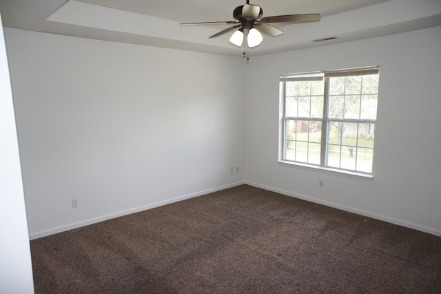 carpeted spare room with a tray ceiling and ceiling fan