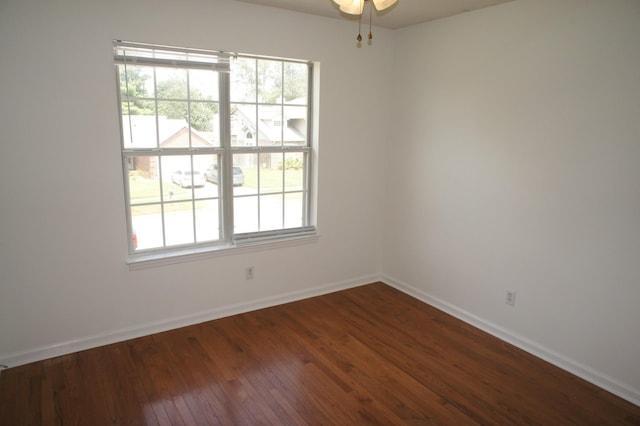 empty room with a wealth of natural light and dark hardwood / wood-style floors