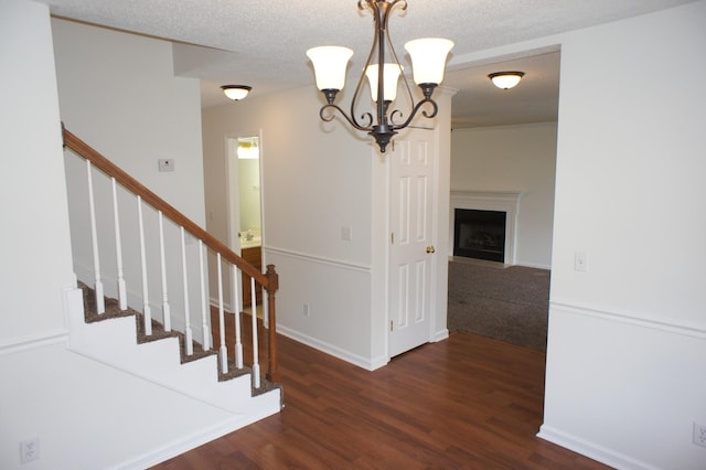 unfurnished dining area with a textured ceiling, dark hardwood / wood-style floors, and a notable chandelier