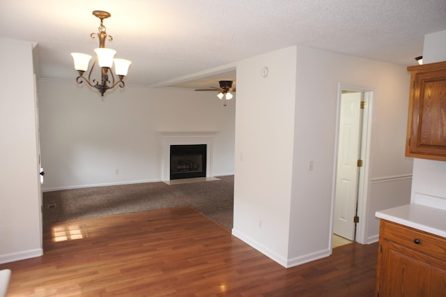 unfurnished living room featuring ceiling fan with notable chandelier, wood-type flooring, and a textured ceiling