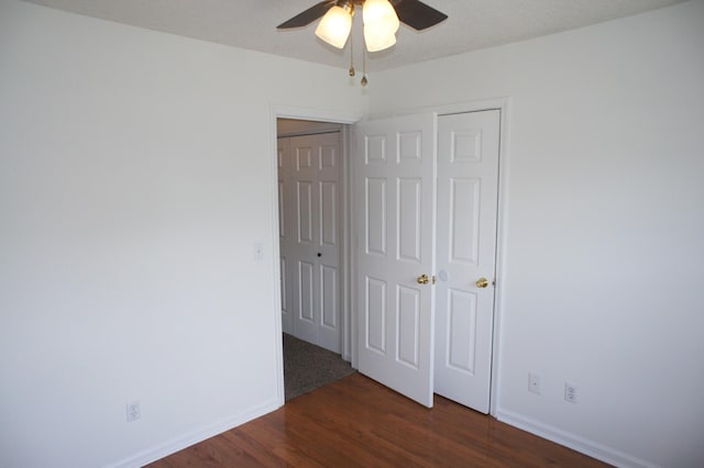 unfurnished bedroom with ceiling fan, a closet, and dark wood-type flooring