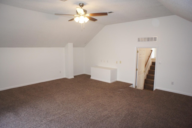 bonus room with a textured ceiling, ceiling fan, vaulted ceiling, and dark colored carpet