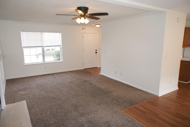 unfurnished living room with dark colored carpet, ceiling fan, ornamental molding, and a textured ceiling