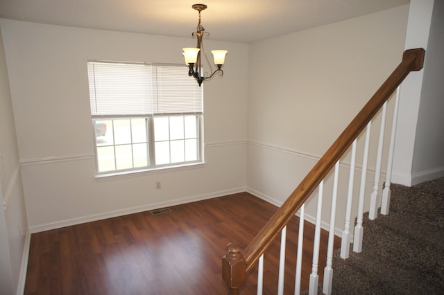 spare room featuring dark wood-type flooring and a chandelier