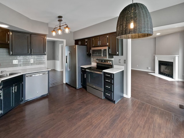 kitchen featuring dark hardwood / wood-style flooring, dark brown cabinetry, hanging light fixtures, and appliances with stainless steel finishes