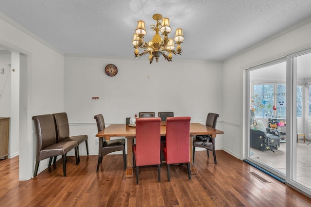 dining room featuring a notable chandelier, dark hardwood / wood-style flooring, a textured ceiling, and crown molding