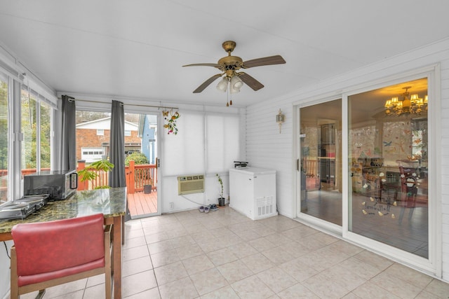 sunroom with ceiling fan with notable chandelier and a wall mounted AC