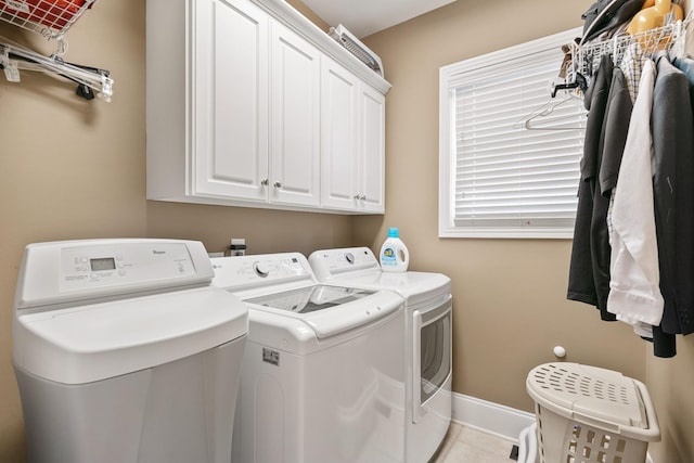 laundry room featuring light tile patterned flooring, cabinets, and washing machine and clothes dryer