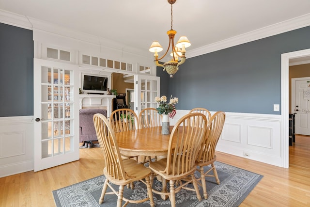 dining area with crown molding, hardwood / wood-style floors, french doors, and an inviting chandelier