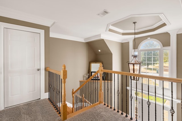 hallway with a healthy amount of sunlight, ornamental molding, a tray ceiling, and an inviting chandelier