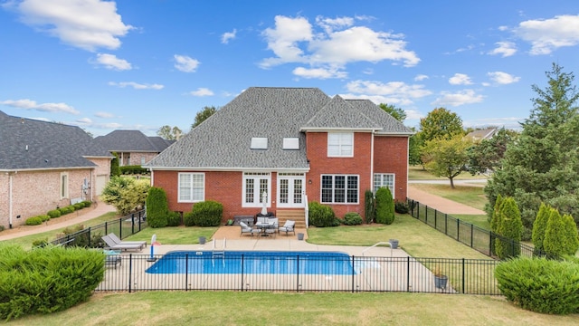 back of property featuring a lawn, a patio, and a fenced in pool