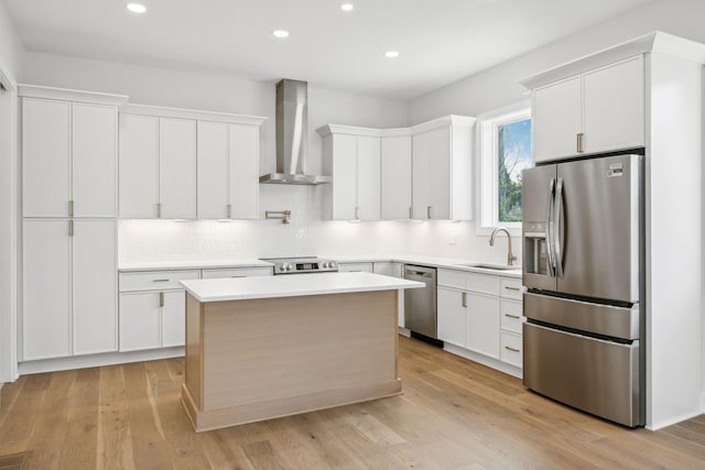 kitchen with white cabinetry, a center island, wall chimney range hood, and appliances with stainless steel finishes