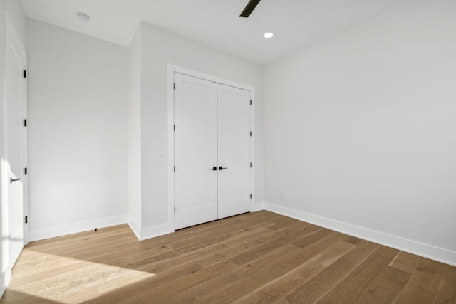 unfurnished bedroom with ceiling fan, wood-type flooring, and a closet