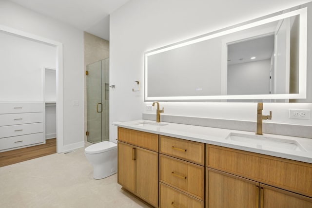 bathroom featuring vanity, toilet, and a shower with door