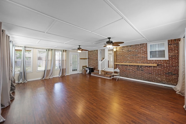 unfurnished living room with ceiling fan, brick wall, and dark hardwood / wood-style floors