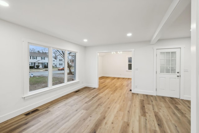 unfurnished living room featuring beam ceiling and light hardwood / wood-style floors