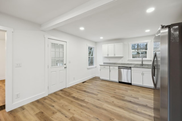 kitchen with beamed ceiling, white cabinets, sink, and appliances with stainless steel finishes