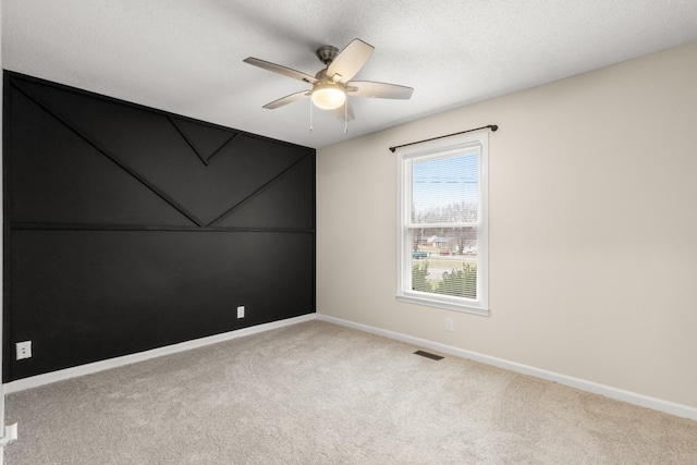 spare room featuring ceiling fan, carpet, and a textured ceiling