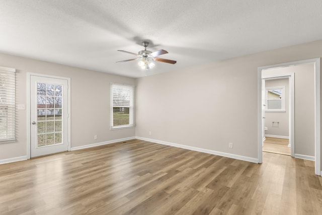 empty room featuring ceiling fan, light hardwood / wood-style flooring, and a textured ceiling