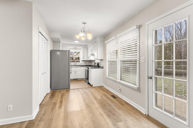 kitchen featuring hanging light fixtures, light hardwood / wood-style flooring, a chandelier, white cabinets, and appliances with stainless steel finishes