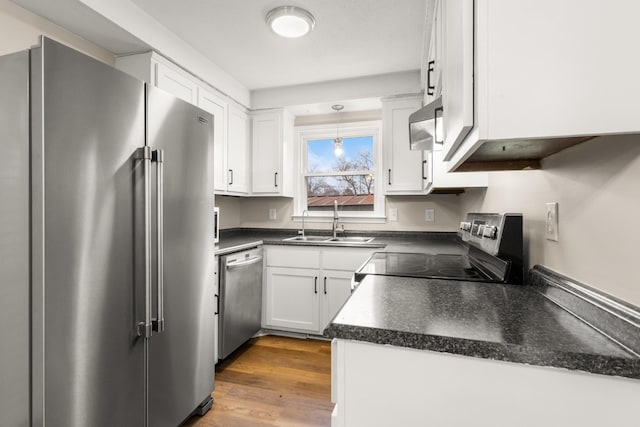 kitchen with stainless steel appliances, sink, decorative light fixtures, hardwood / wood-style floors, and white cabinetry