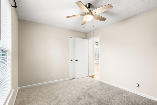 unfurnished bedroom featuring a closet, light colored carpet, and ceiling fan