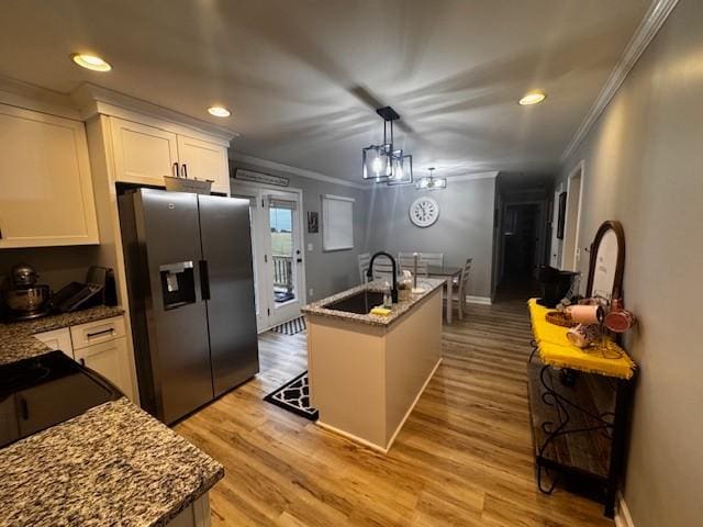 kitchen featuring a center island with sink, decorative light fixtures, white cabinetry, and stainless steel fridge with ice dispenser