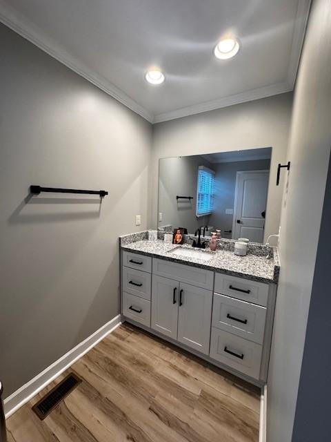 bathroom with hardwood / wood-style floors, vanity, and crown molding