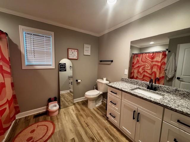 bathroom featuring wood-type flooring, vanity, toilet, and ornamental molding