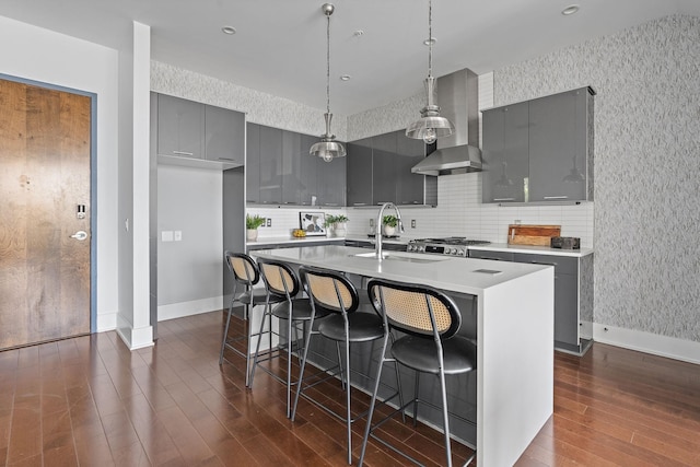 kitchen with decorative backsplash, sink, a breakfast bar, and an island with sink