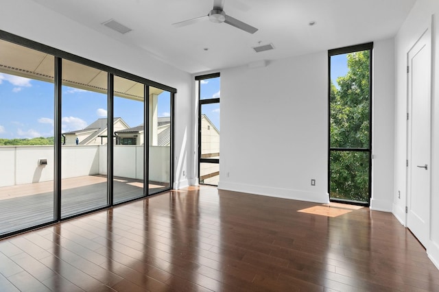 unfurnished room with floor to ceiling windows, hardwood / wood-style floors, and ceiling fan