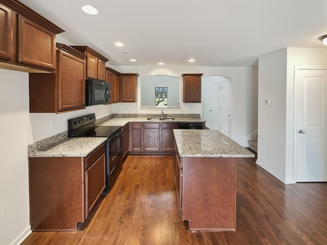 kitchen featuring a center island, black appliances, sink, light stone countertops, and dark hardwood / wood-style flooring