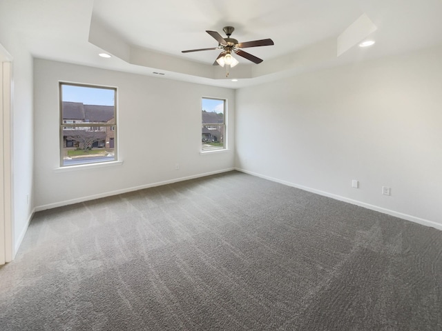 carpeted empty room with a tray ceiling and ceiling fan