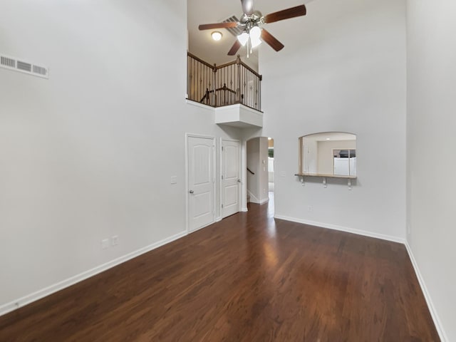 unfurnished living room featuring a high ceiling and dark hardwood / wood-style flooring