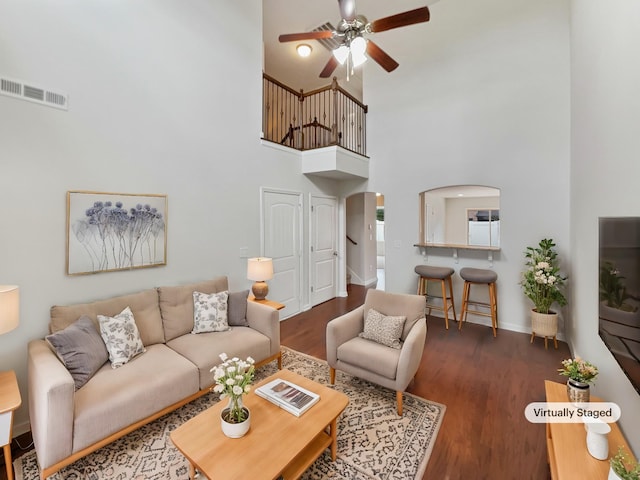 living room with ceiling fan, dark wood-type flooring, and a high ceiling