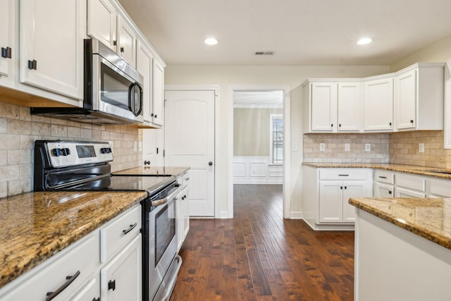 kitchen with white cabinetry, backsplash, dark hardwood / wood-style flooring, stainless steel appliances, and light stone countertops