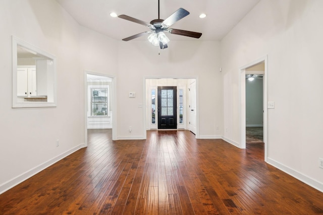 unfurnished living room featuring dark hardwood / wood-style flooring, ceiling fan, and a high ceiling