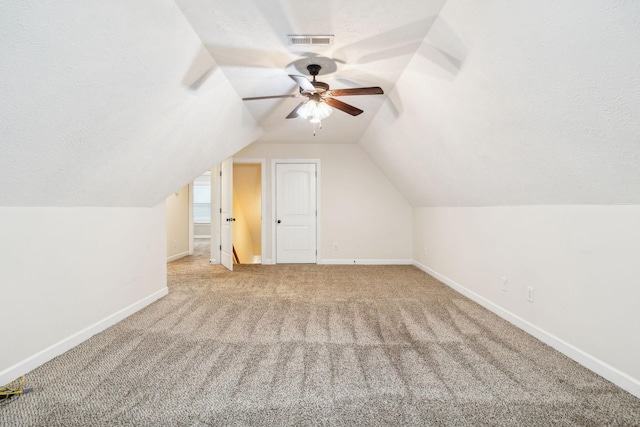 bonus room featuring vaulted ceiling, light colored carpet, a textured ceiling, and ceiling fan