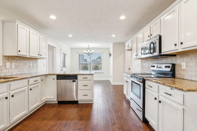 kitchen featuring stainless steel appliances, dark hardwood / wood-style floors, kitchen peninsula, and white cabinets